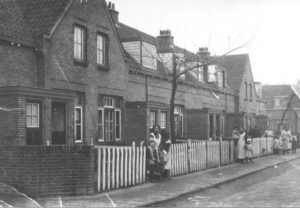 De Franklinstraat, omstreeks 1918. Links staat mevrouw van Dijk met haar kinderen. In het midden staat mevrouw Post. Zij woonde op nummer 15. Wie helemaal achteraan staan is onbekend. Links ziet u duidelijk de uitbouw die men indertijd speciaal bedoelde als ‘klompenhokje’: de ruimte waar men zijn klompen uittrok. Het huis betrad men op kousenvoeten.