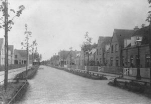 De De Lessepsstraat in zijn nog jonge jaren. De bouw is nog maar nauwelijks gereed. Achteraan staat zelfs nog iets dat op een verhuiswagen lijkt. De foto uit 1917 toont u wel een ander straatbeeld dan dat van tegenwoordig. Wat te zeggen van de openbare verlichting bijvoorbeeld. Zoiets kun je toch geen ‘lantaarnpalen’ noemen? De bomen zouden eerst nog uitgroeien tot grote kastanjes, om dan in de Tweede Wereldoorlog goeddeels in de kachels van de kleumende Zuilenaren verdwijnen. Zo zorgden zij voor nog wat warmte in de barre winter van 1944.