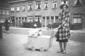 Mevrouw Jansen uit de Ampèrestraat staat in de Galvanistraat met een kinderwagen waarin haar neefje ligt.